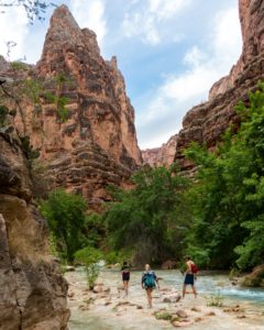 three people wading through river